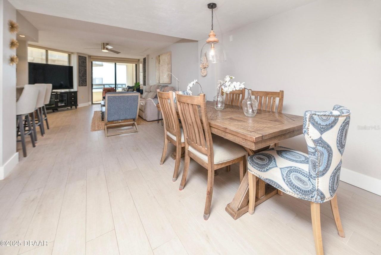 Photo 13 of 20: Enjoy an open, connected floor plan that brings together the dining room, kitchen, and living area. Neutral finishes and a direct view toward the oceanfront balcony enhance the relaxed coastal atmosphere.