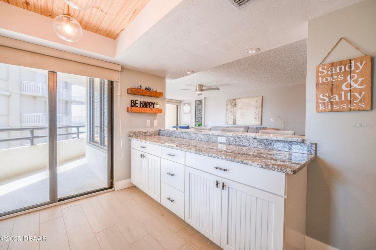 Photo 11 of 20: An extended granite breakfast bar provides additional seating and serving space, while ample lower cabinetry offers convenient storage. Sliding glass doors bring natural light into this open and inviting area.