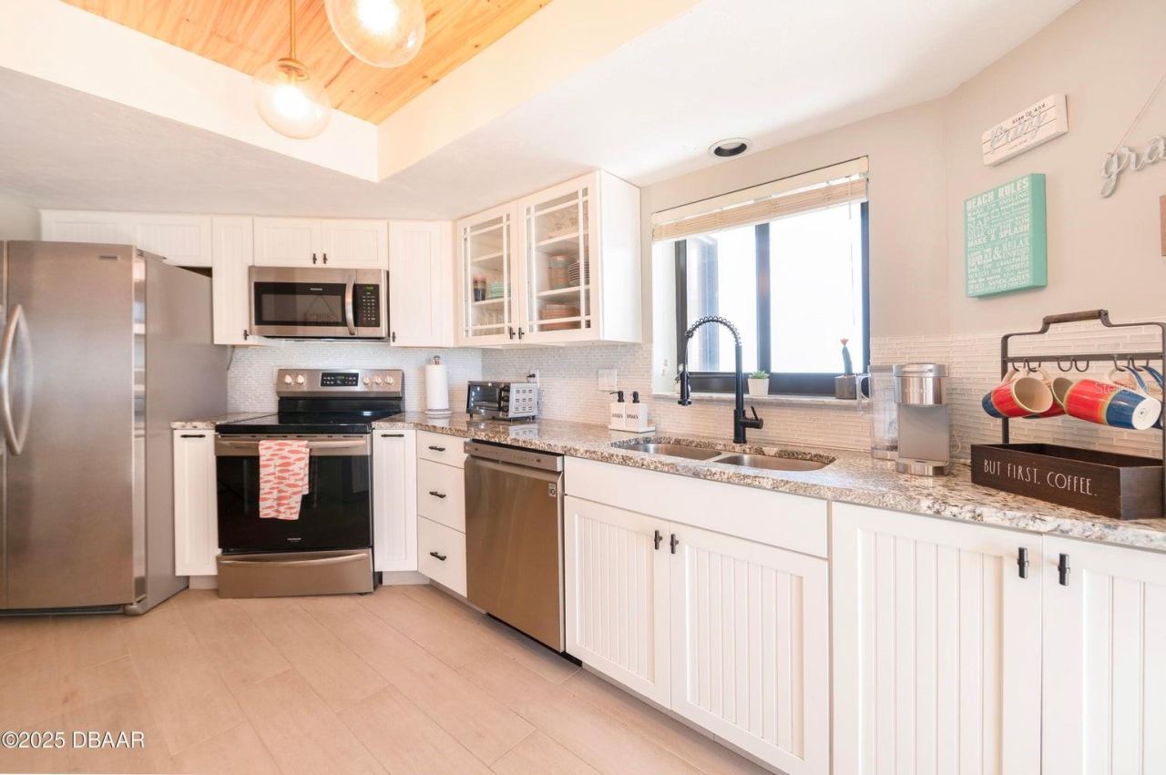 Photo 10 of 20: This thoughtfully designed kitchen showcases stainless steel appliances, generous counter space, white cabinetry with contrasting hardware, and a double-basin sink with a modern black faucet.