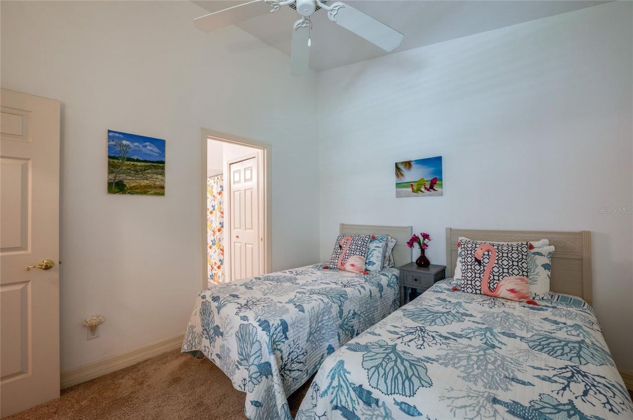Photo 15 of 20: Inviting bedroom layout framed by soft neutral walls, high ceilings, and plush carpeting. An open doorway offers direct access to an adjacent full bathroom.