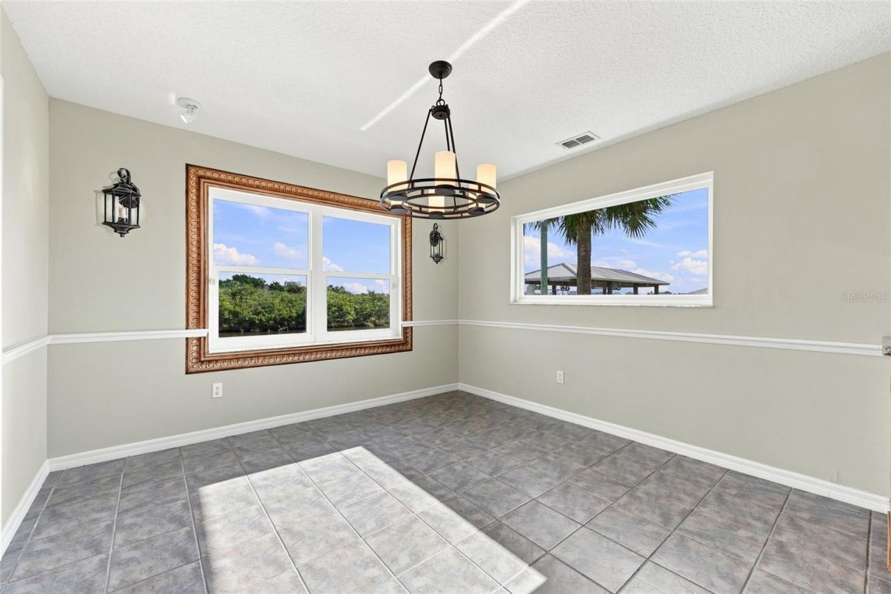 Photo 18 of 20: Breakfast nook — Breakfast nook with oversized picture-frame window overlooking the canal, second window with palm tree view, and wagon-wheel chandelier.