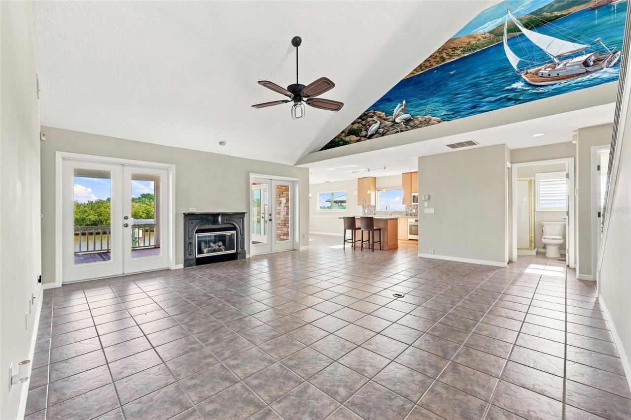 Photo 10 of 20: Great room — Vaulted great room with gas fireplace, French doors to a canal-view balcony, tile flooring, and an open sightline to the kitchen and staircase.