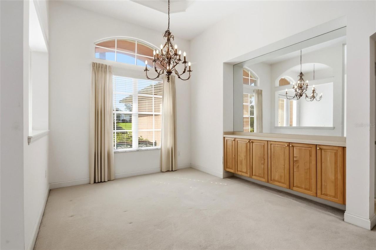 Photo 8 of 20: Formal dining room with an arched window, chandelier, and built-in server and storage.