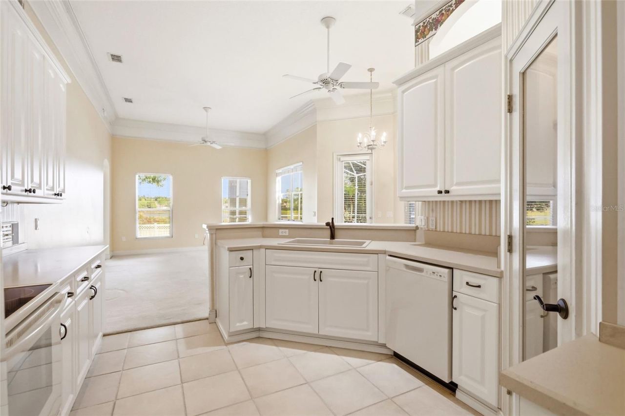 Photo 3 of 20: White kitchen cabinetry, generous counter space, and a breakfast bar connect the kitchen tothe family room and breakfast nook.
