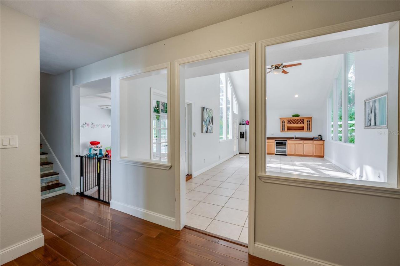Photo 8 of 20: Hallway perspective highlighting warm laminate floors, architectural interior cutouts, and seamless transitions into light-filled open rooms.