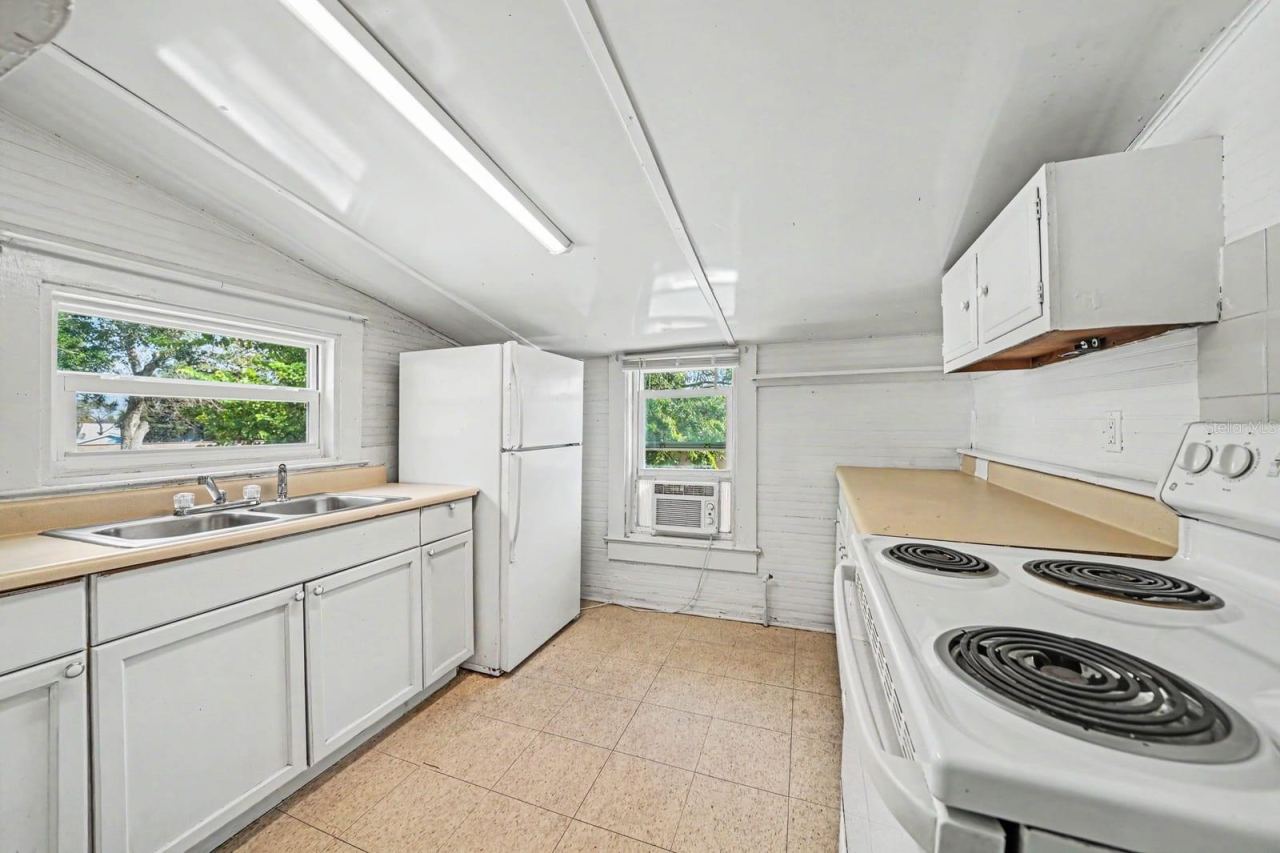Photo 13 of 20: Galley Kitchen with White Appliances, Coil Range & Window Overlooking Trees