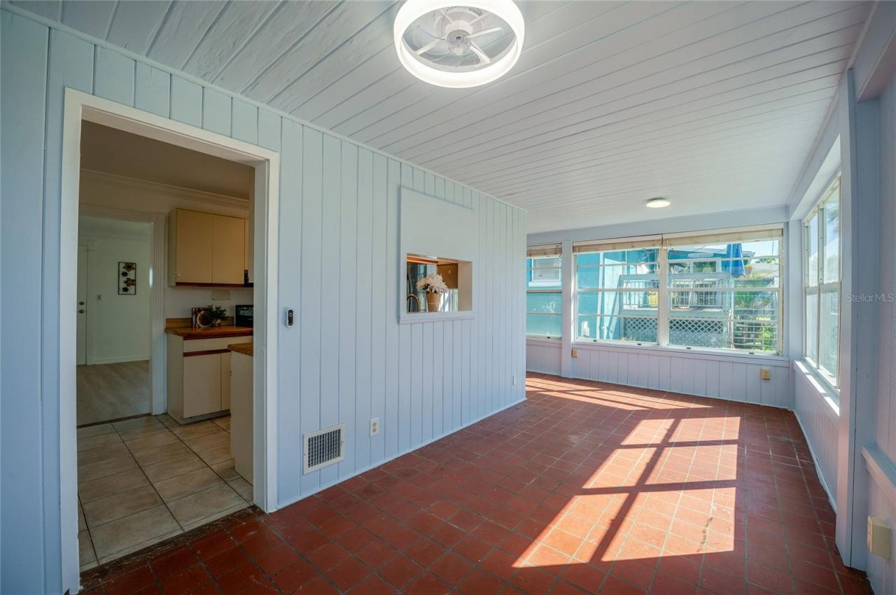 Photo 11 of 20: Dinning area featuring light blue wood-paneled walls, warm terracotta floor tiles, and abundant wrap-around windows. A passthrough window connects back to the kitchen for added convenience.