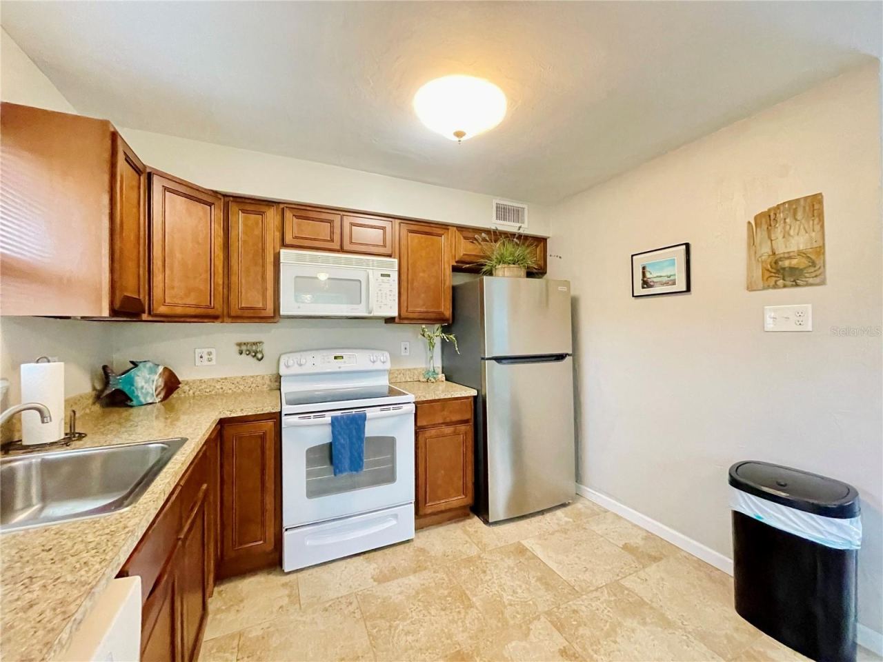 Photo 12 of 20: A closer view highlights the abundant cabinetry and counter space, stainless steel refrigerator, electric range, built-in microwave, and convenient workspace.