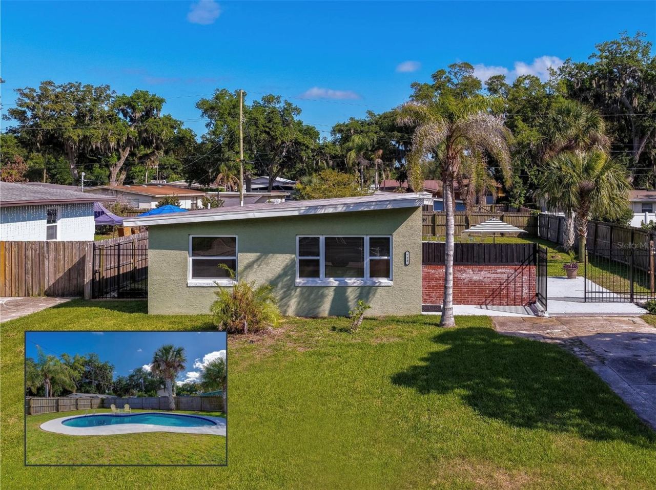 Photo 1 of 20: Charming 1-story home with modern design with spacious fenced yard, private pool, and tropical landscaping with mature palms and a bright, open outdoor setting.