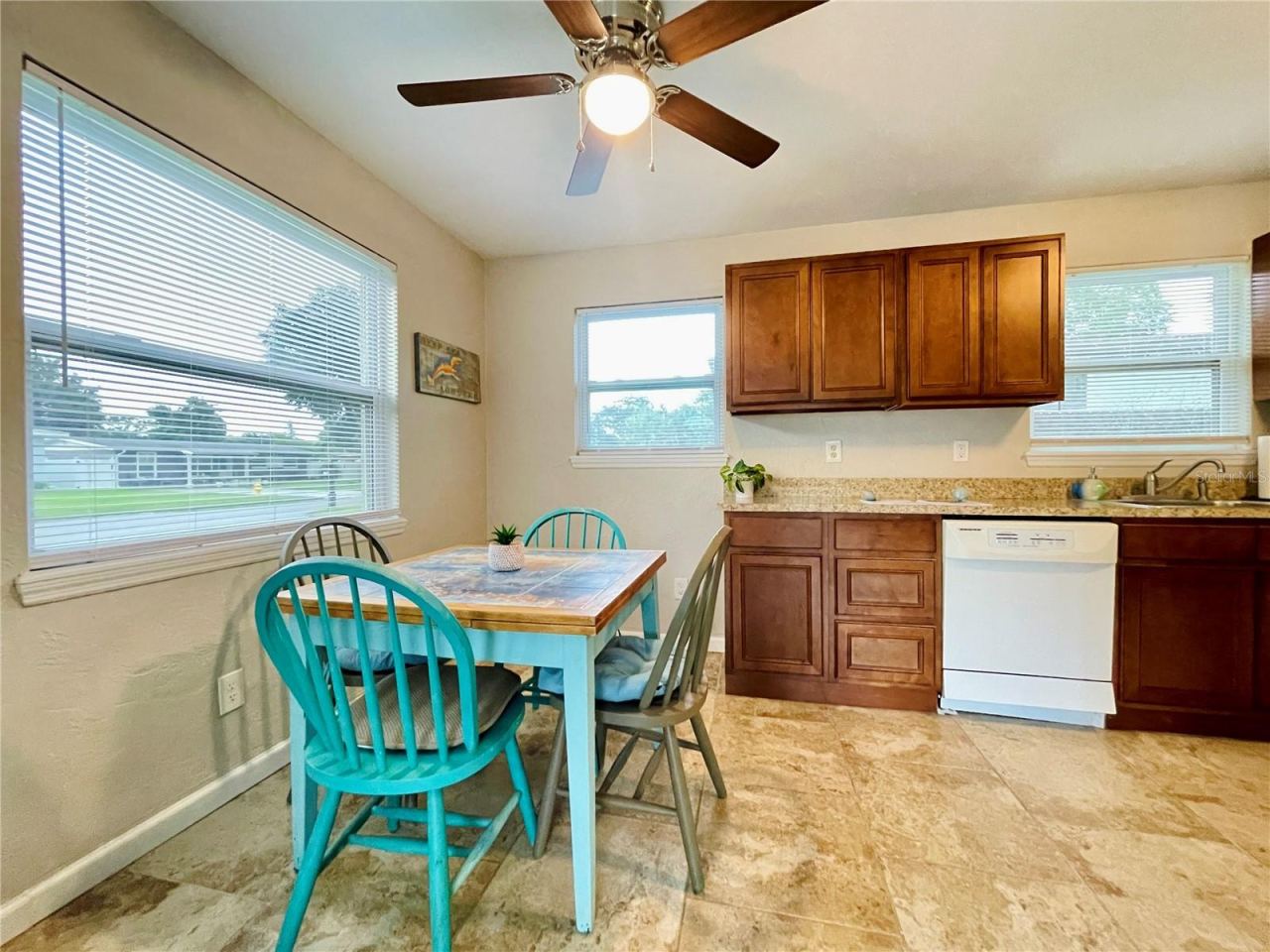 Photo 8 of 20: Charming dining niche featuring a vibrant blue table setup tucked next to an expansive kitchen counter with warm wood cabinetry.