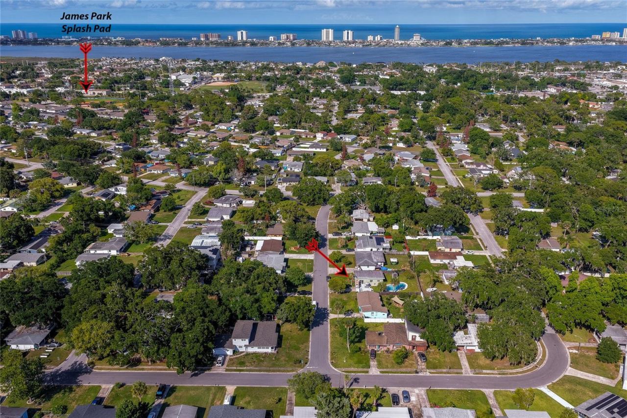 Photo 5 of 20: Wide aerial perspective highlighting the property’s location within the neighborhood, with a red arrow pointing toward the home and another local attractions and nearby coastal waters.