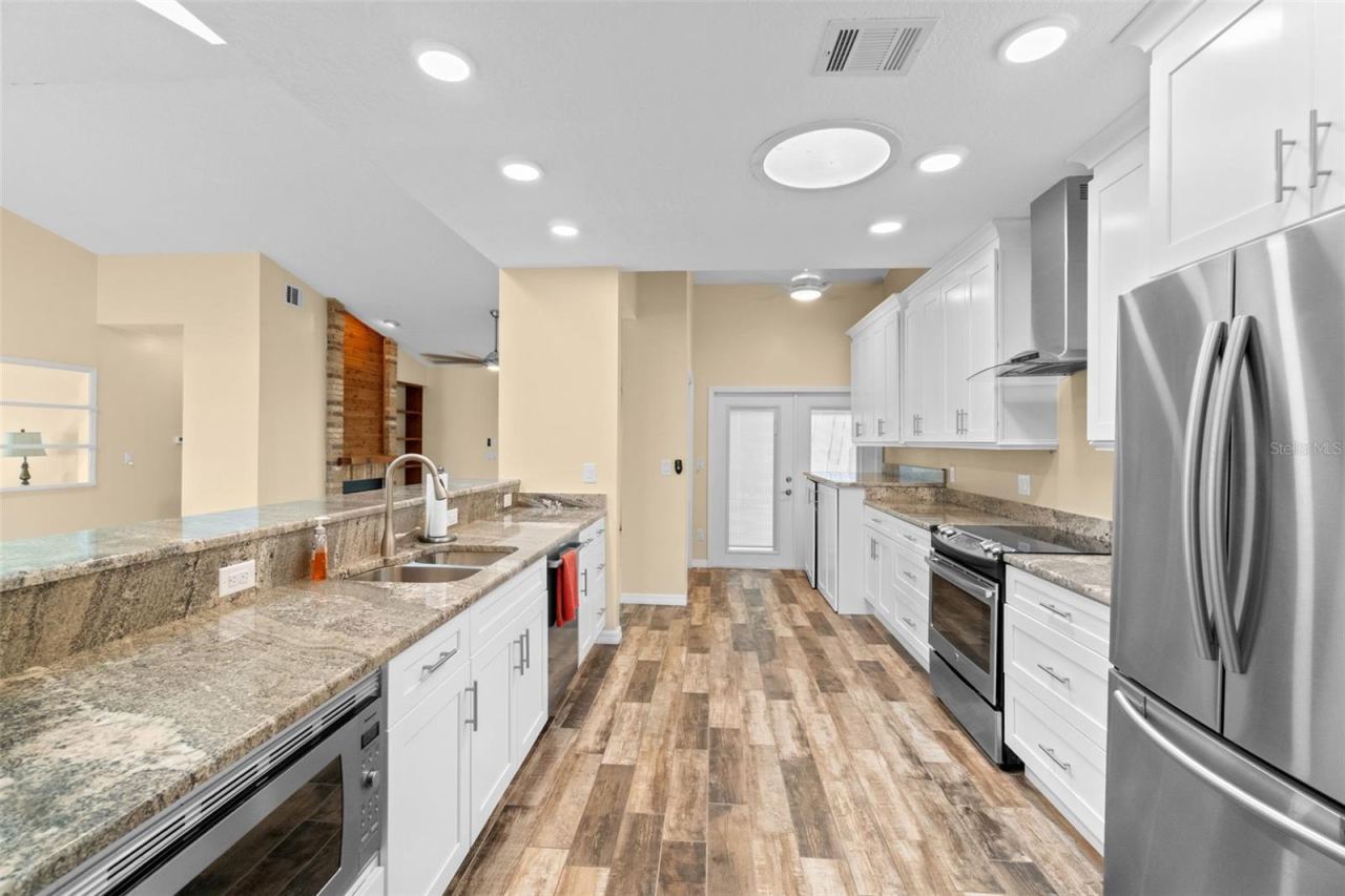 Photo 15 of 20: kitchen with open breakfast bar and laundry room with French doors to screened in lanai