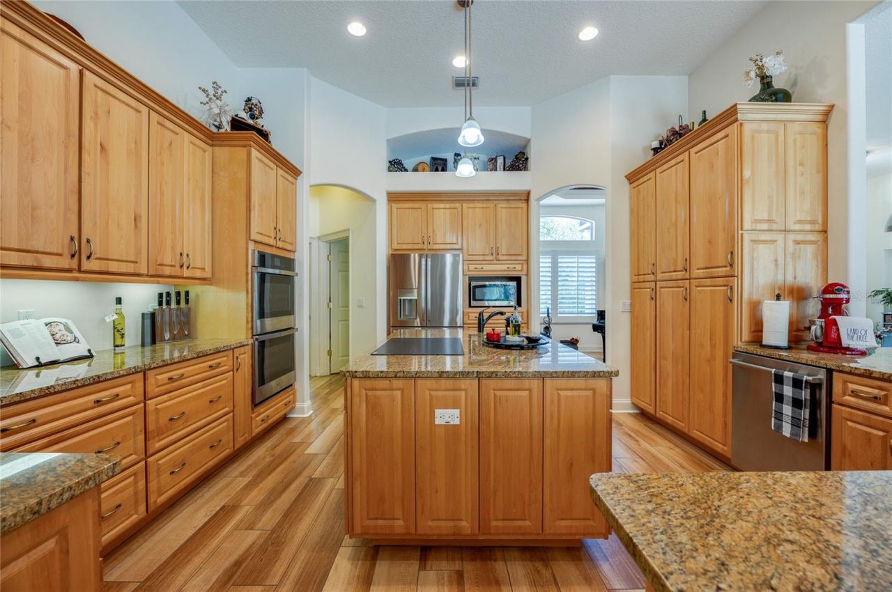Photo 14 of 20: Spacious chef's kitchen centered around a multi-functional island with granite countertops, integrated appliances, and a built-in cooktop.