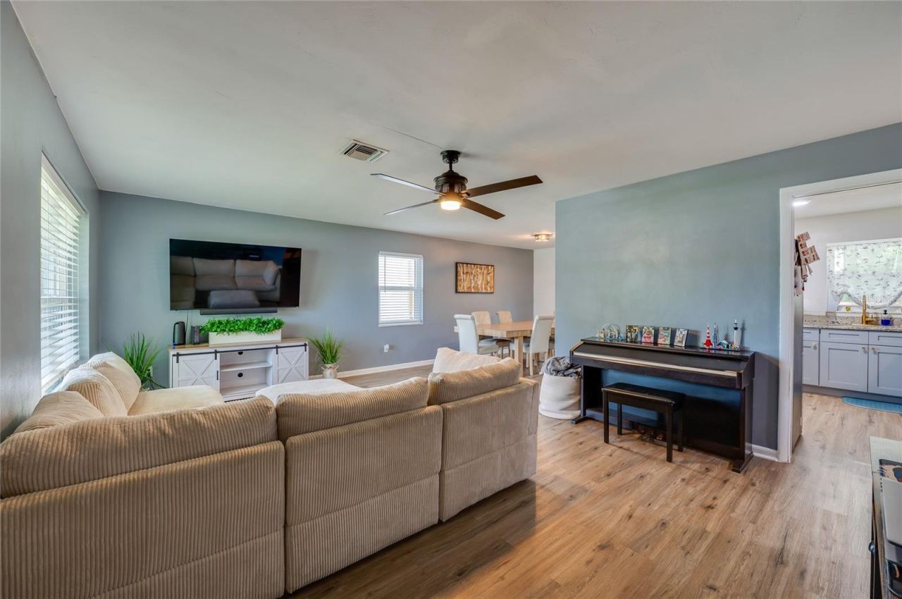 Photo 6 of 20: Expansive open-concept living space with LVP flooring, ceiling fans, and seamless flow into adjoining dining and kitchen areas.