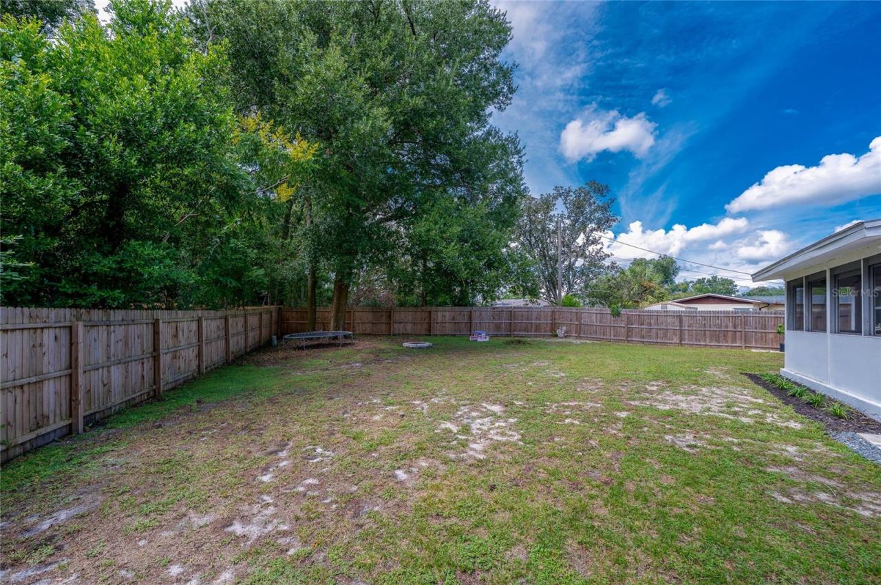 Photo 20 of 20: Spacious backyard enclosed by a full wooden privacy fence and lined with mature trees along the perimeter.