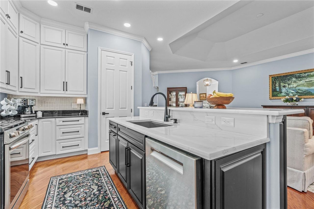 Photo 19 of 20: Quartz counters on the island surround a large, single bowl stainless steel sink; The door adjacent to the island is the closet pantry