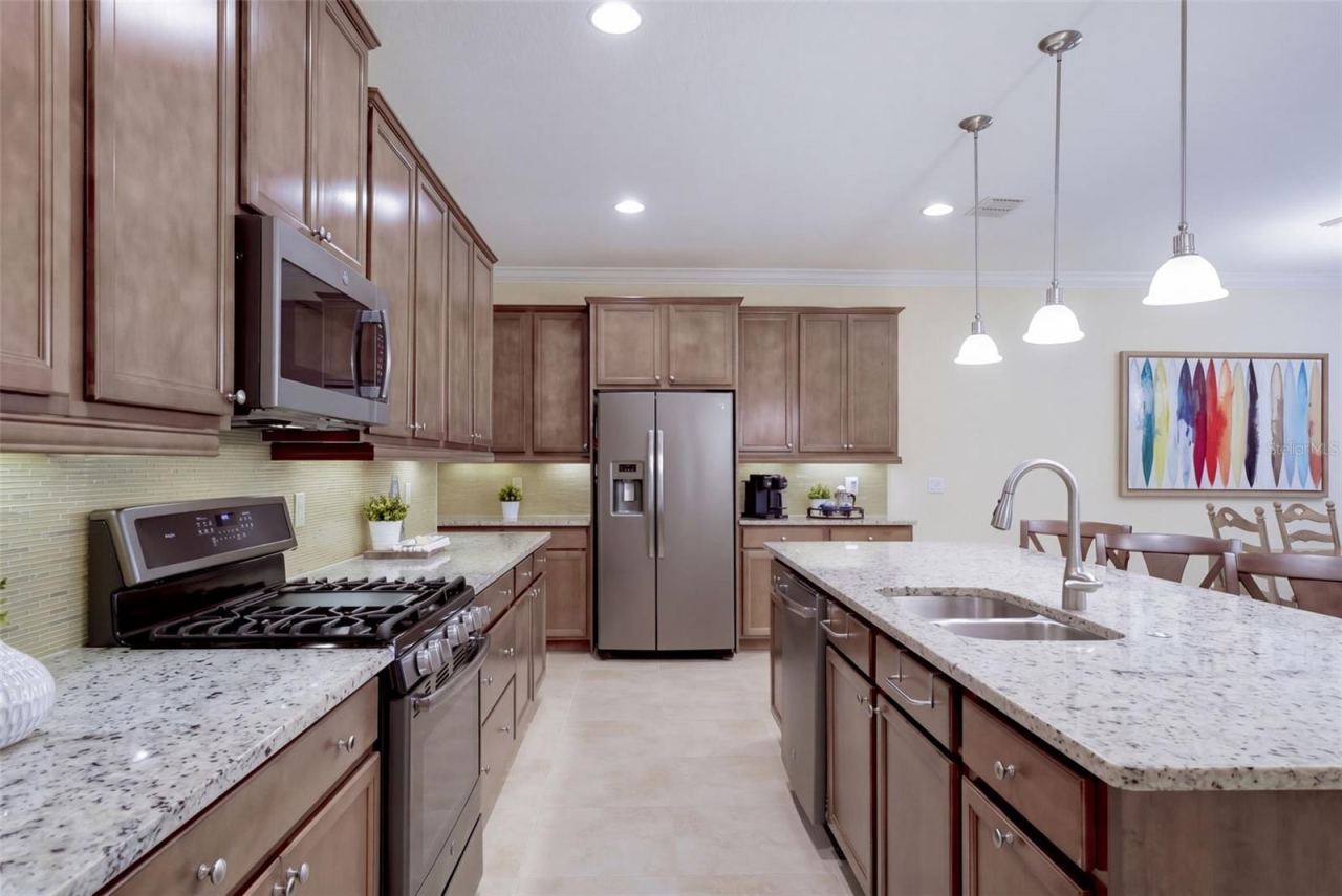 Photo 6 of 20: Kitchen w/ a 5-burner natural gas convention range, stainless steel appliances & pendant lighting above breakfast island