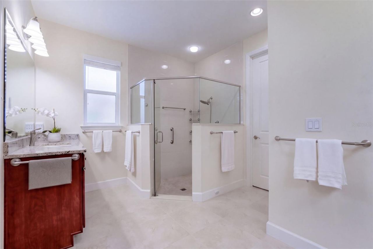 Photo 17 of 20: Primary Bathroom w/ separate granite vanities, glass enclosed walk-in shower, bench seat & a spacious walk-in closet