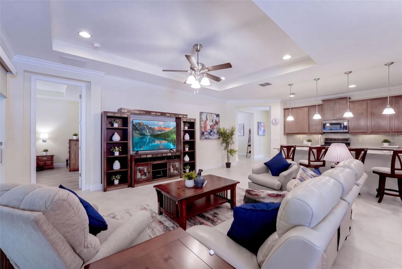 Photo 12 of 20: Great Room w/ crown molding, recessed lighting, tray ceiling & a ceiling fan