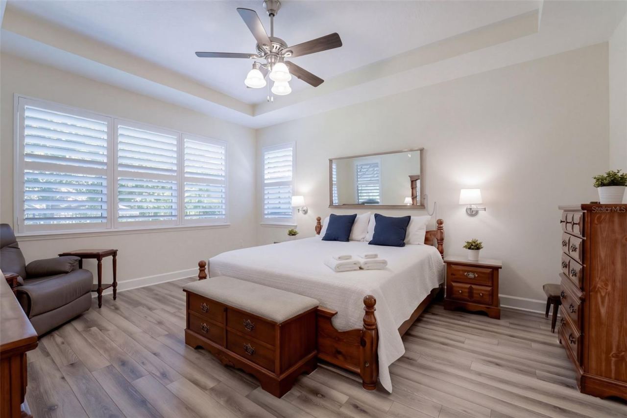 Photo 15 of 20: 14' x 17' Primary Bedroom w/ a luxury vinyl floor, tray ceiling & a ceiling fan