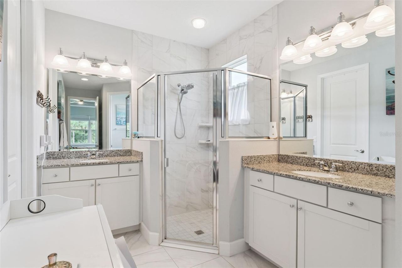 Photo 18 of 20: 8' x 15' Primary Bathroom w/ separate granite countertop vanities, glass enclosed walk-in shower & bench seat