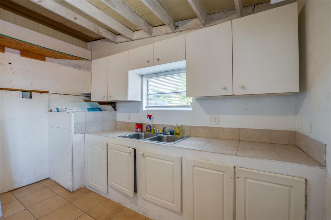 Photo 17 of 20: Dedicated utility space includes a double-basin sink, countertop workspace, upper and lower cabinetry, and a window above the sink.