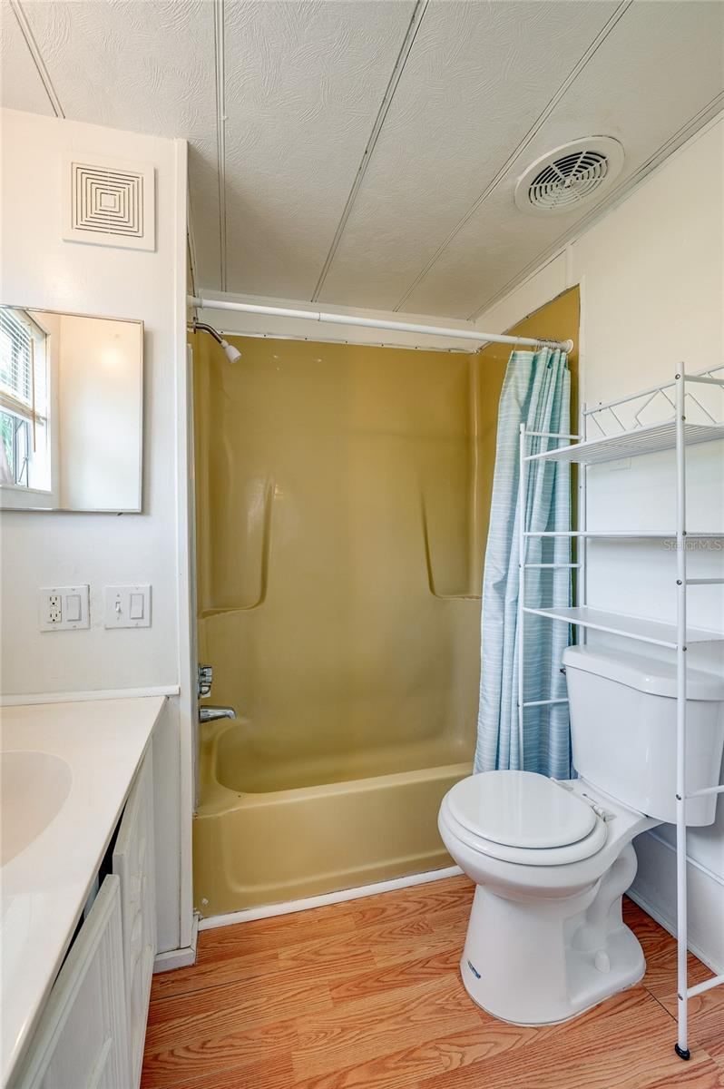 Photo 16 of 20: Full bathroom with a tub/shower combination, vanity, window for natural light, and additional over-toilet storage.