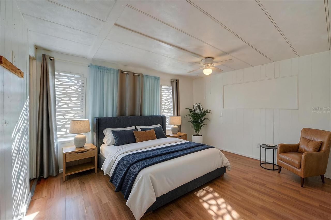 Photo 14 of 20: Virtually Staged - Spacious bedroom with paneled walls, a ceiling fan, and multiple windows that bring in abundant natural light.