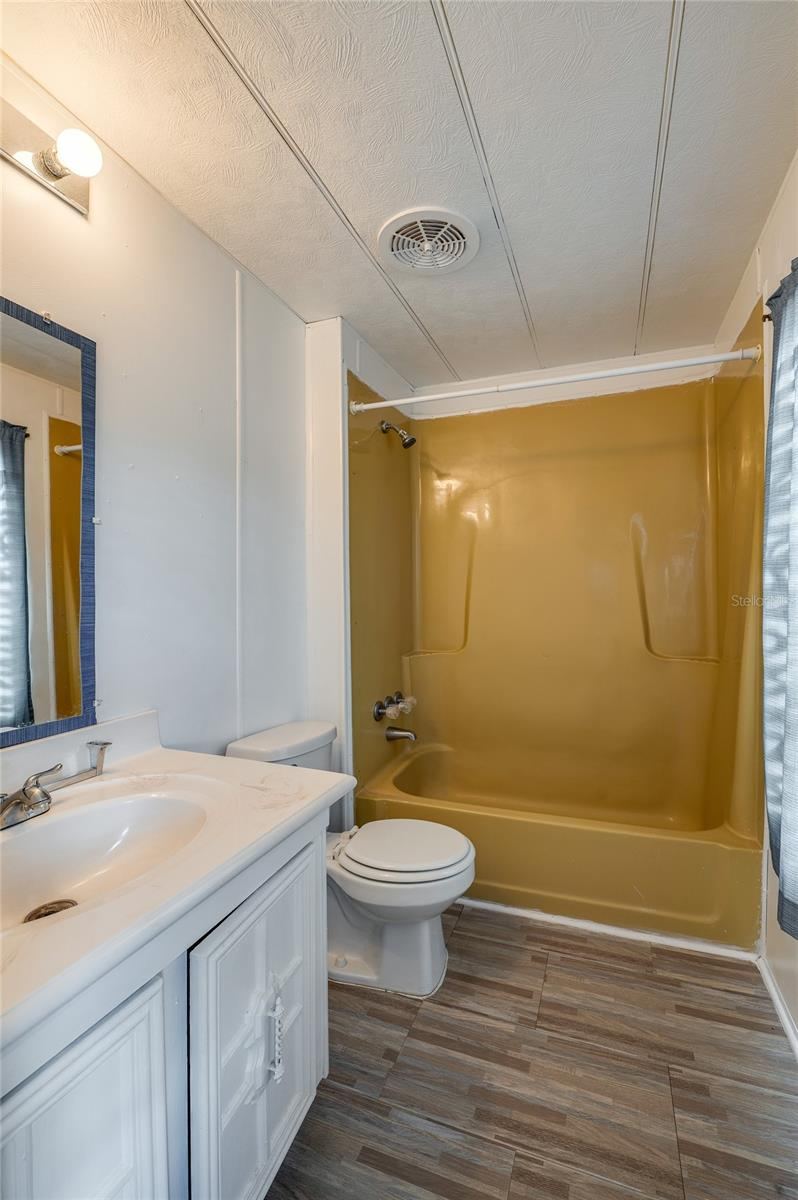 Photo 13 of 20: Full bathroom features a tub/shower combination, vanity with storage, and a window providing natural light.