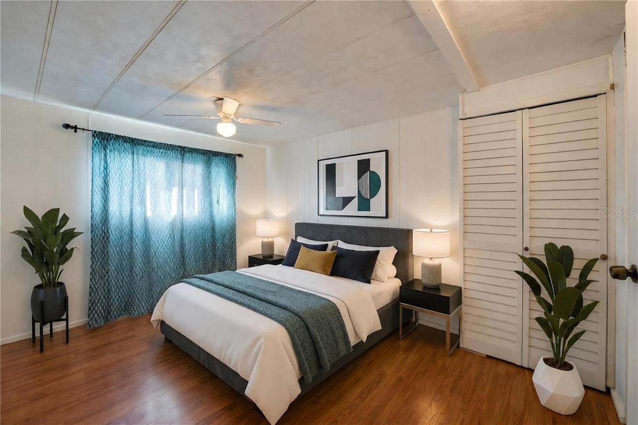 Photo 10 of 20: Virtually Staged - Bright, versatile bedroom with paneled walls, a ceiling fan with light, a large window for natural light, and a louvered-door closet.