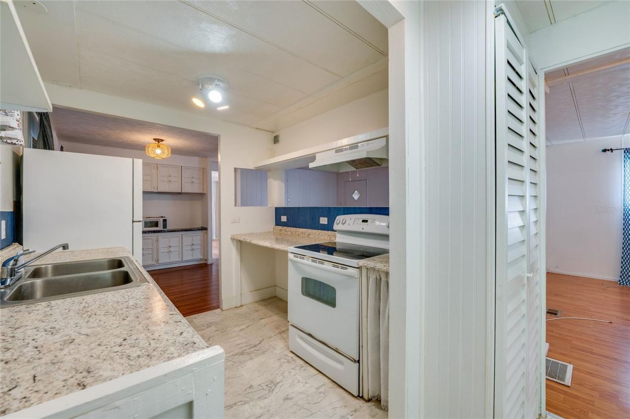 Photo 9 of 20: Functional eat-in kitchen features generous counter space, a double-basin sink, range with hood, refrigerator, and a pass-through opening that connects with the adjoining living area.