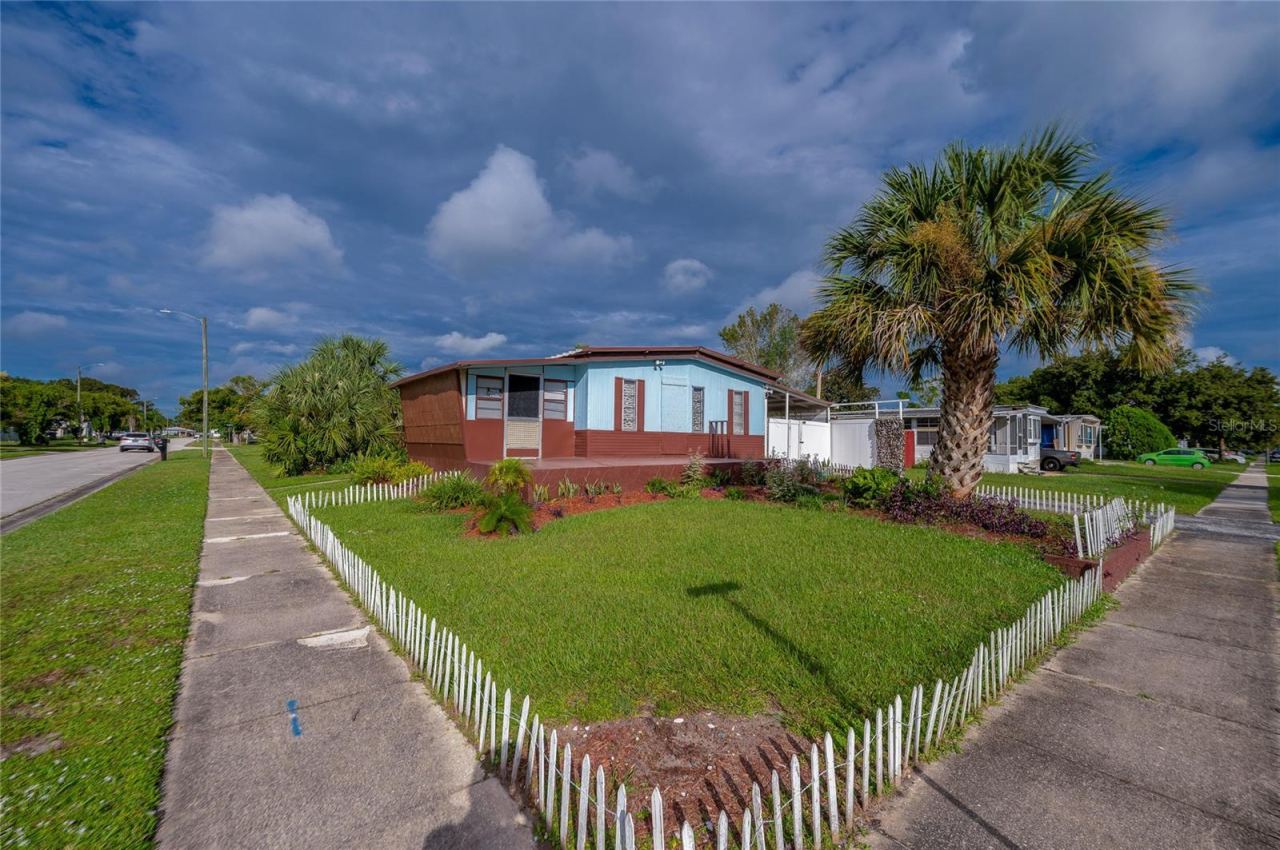 Photo 1 of 20: Wide exterior view highlights the corner setting, lawn, tropical landscaping, and low decorative fencing surrounding the front yard.