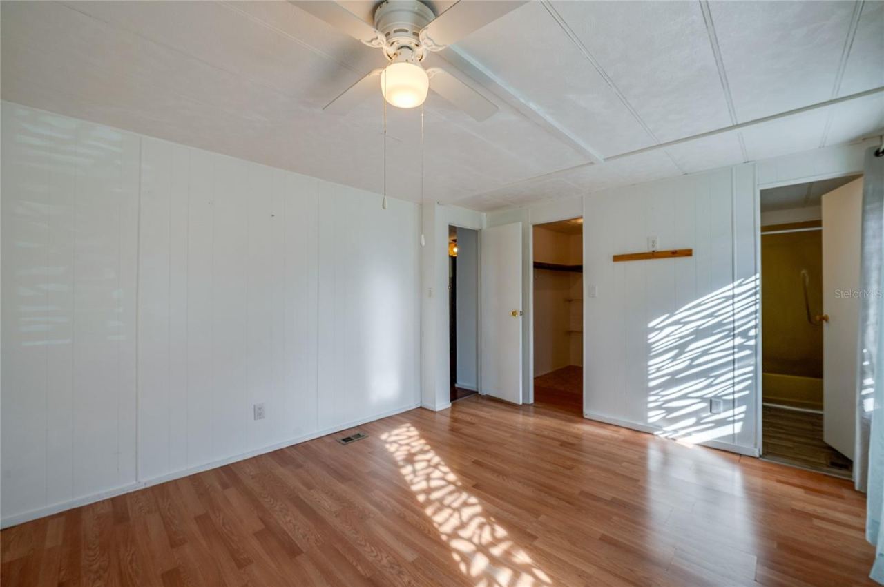 Photo 11 of 20: Additional view highlights the room’s open floor area, ceiling fan, and convenient access to a walk-in closet and adjoining bathroom.