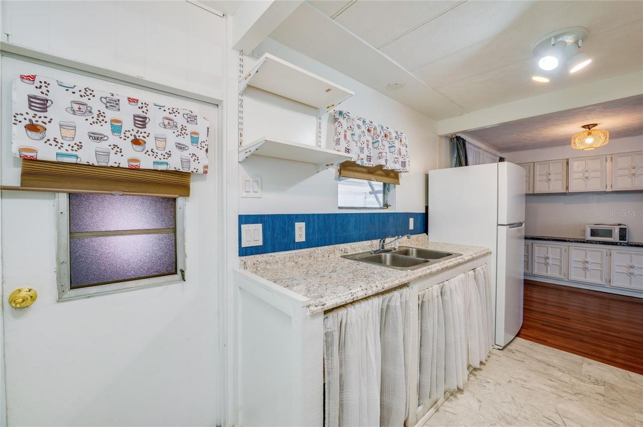 Photo 8 of 20: Additional kitchen view showcases the long countertop and sink area, open shelving, and convenient connection to the adjacent dining space.