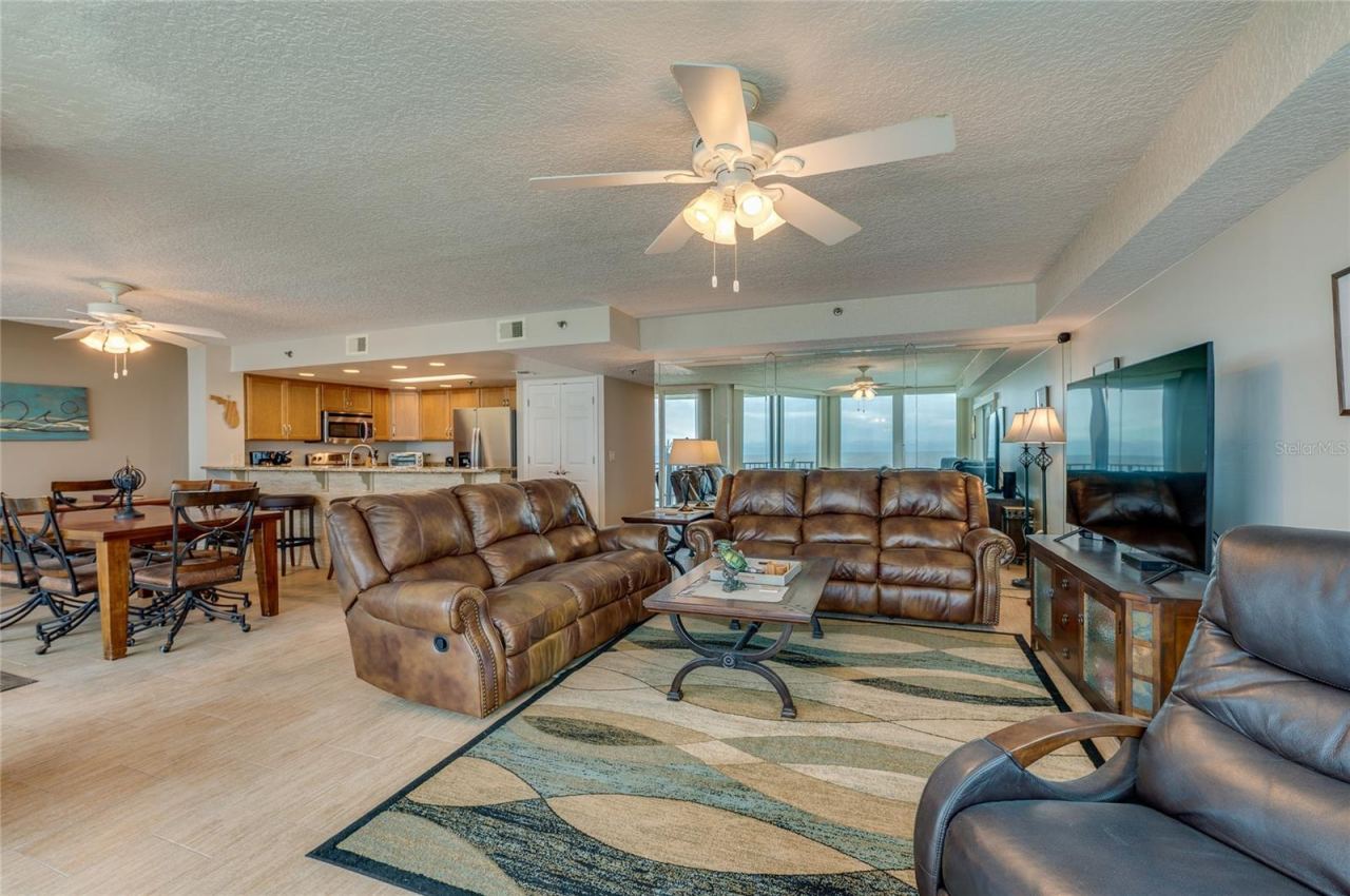 Photo 12 of 20: The spacious open-concept design combines living, dining, and kitchen areas, offering coastal views, recessed lighting, and a mirrored accent wall that enhances the natural light.