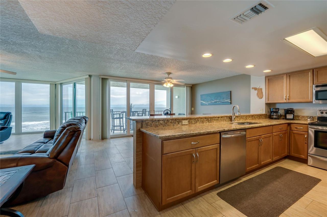 Photo 16 of 20: This open kitchen boasts granite countertops, stainless steel appliances, and a breakfast bar overlooking the ocean-facing dining space—perfect for entertaining or everyday living.