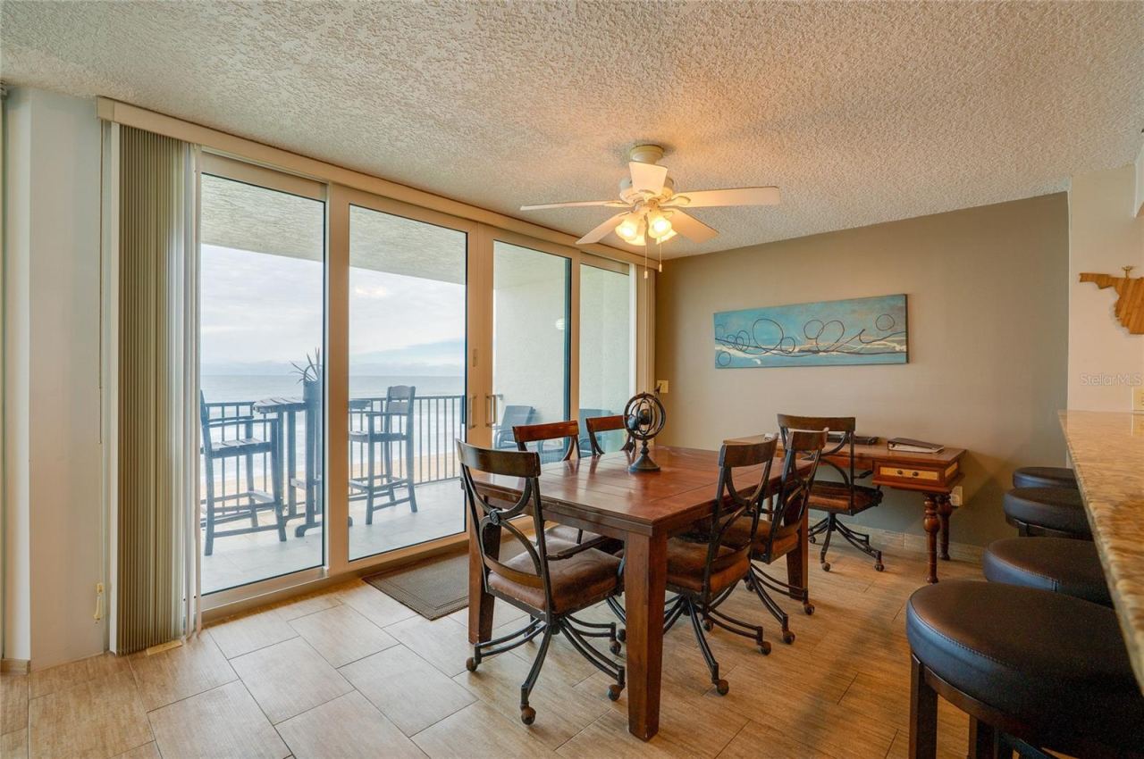 Photo 13 of 20: A spacious dining area with sliding glass doors offers direct access to the balcony and sweeping coastal views perfect for gathering with friends or enjoying sunset dinners.