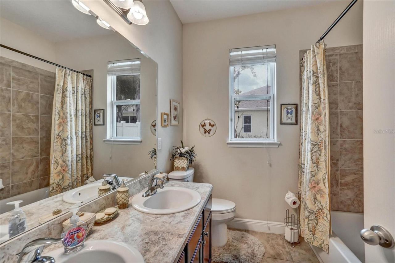 Photo 18 of 20: Second BathroomGuest bathroom featuring a spacious vanity, tiled walls, tub, and natural light.