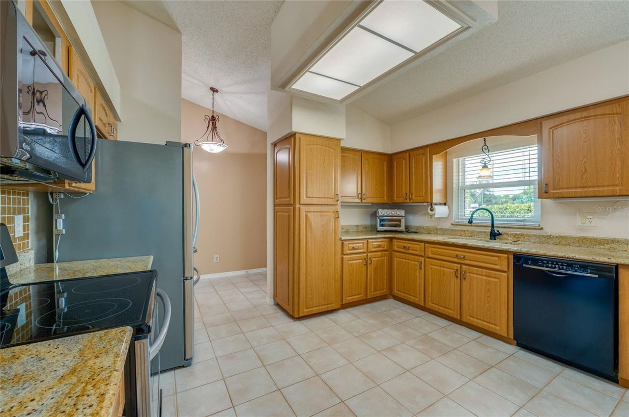 Photo 9 of 20: Well-appointed kitchen featuring solid wood cabinets, granite countertops, black and stainless steel appliances, and tile flooring.